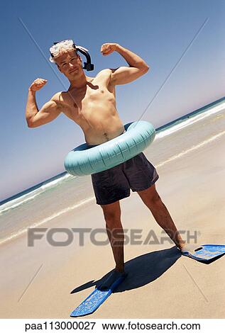 Man wearing snorkeling gear and inner tube, flexing at the beach. View Large Photo Image Stock Photo - Man wearing snorkeling gear and inner tube, flexing at the beach.. Fotosearch