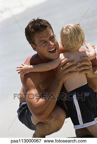 Rear view of young child hugging man on the beach. View Large Photo Image Stock Photo - Rear view of young child hugging man on the beach.. Fotosearch