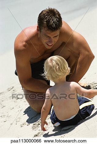 Rear view of young child sitting on beach looking at man. View Large Photo Image Stock Photograph - Rear view of young child sitting on beach looking at man.. Fotosearch