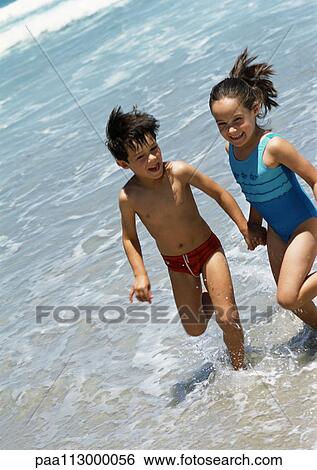 Two children holding hands in the water at the beach. View Large Photo Image Stock Photograph - Two children holding hands in the water at the beach.. Fotosearch