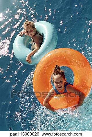 Two little girls floating in inflatable rings in water, high angle view View Large Photo Image Stock Photograph - Two little girls floating in inflatable rings in water, high angle view. Fotosearch
