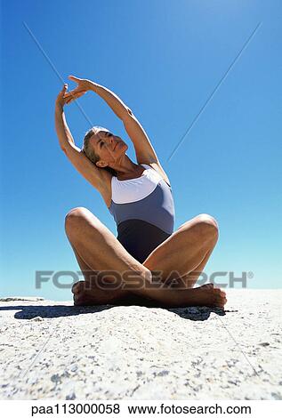 Woman sitting and stretching on the sand. View Large Photo Image Stock Photo - Woman sitting and stretching on the sand.. Fotosearch