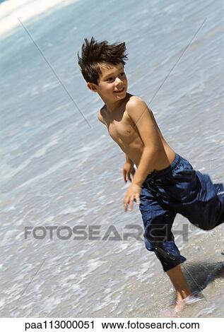 Young boy running in water at the beach. View Large Photo Image Stock Image - Young boy running in water at the beach.. Fotosearch