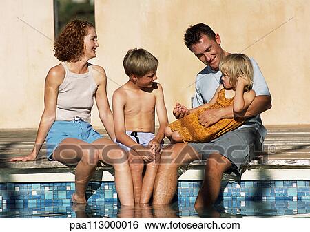 Young family sitting together, feet in pool (frontal view). View Large Photo Image Stock Photograph - Young family sitting together, feet in pool (frontal view). . Fotosearch