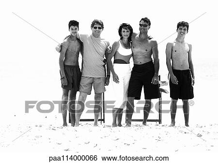 Stock Photograph - Adults standing on beach, b&w. Fotosearch