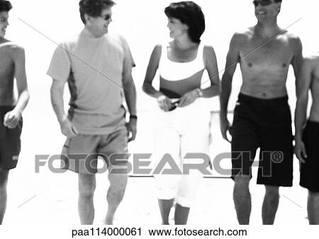 Stock Image - Adults walking on beach, b&w. Fotosearch