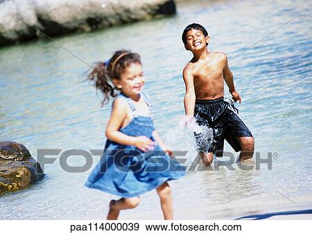 Boy and girl in water, boy splashing, girl running View Large Photo Image Stock Photo - Boy and girl in water, boy splashing, girl running. Fotosearch