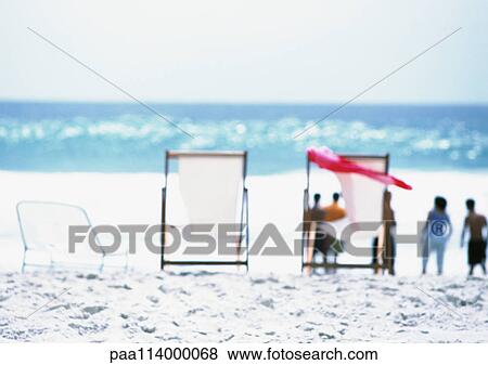 Chairs on beach, adults standing in distance, blurred View Large Photo Image Stock Photo - Chairs on beach, adults standing in distance, blurred. Fotosearch