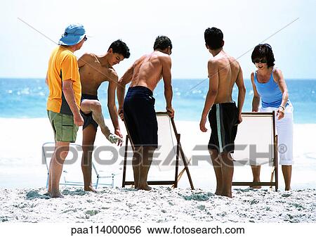 Stock Photograph - Family arranging chairs on beach. Fotosearch
