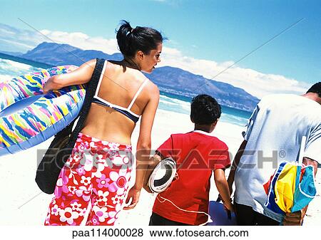 Stock Photo - Family walking on beach, carrying beach things. Fotosearch