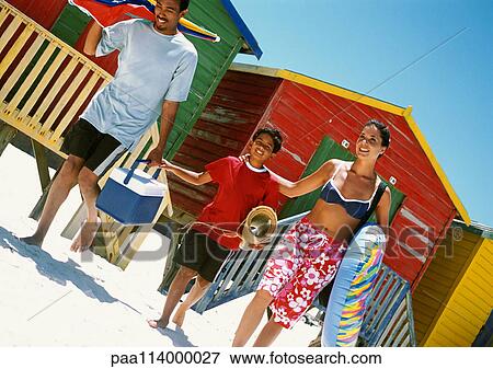 Stock Photo - Family walking onto beach, carrying beach things. Fotosearch