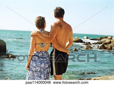 Man and woman standing in front of sea, rear view View Large Photo Image Stock Photograph - Man and woman standing in front of sea, rear view. Fotosearch