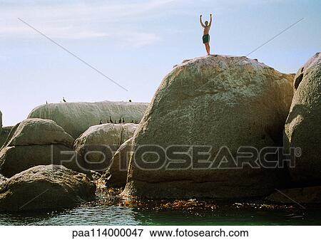 Man standing on rock overlooking sea View Large Photo Image Stock Photo - Man standing on rock overlooking sea. Fotosearch