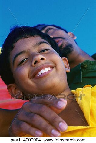 Man standing with hand around boy's shoulder, low angle view, close-up View Large Photo Image Picture - Man standing with hand around boy's shoulder, low angle view, close-up. Fotosearch