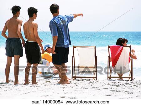 Picture - People on beach, one man pointing. Fotosearch