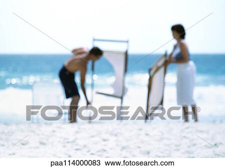Two adults folding chairs on beach, blurred View Large Photo Image Stock Image - Two adults folding chairs on beach, blurred. Fotosearch