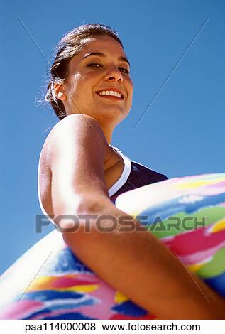 Stock Photo - Woman holding inner tube, low angle view. Fotosearch