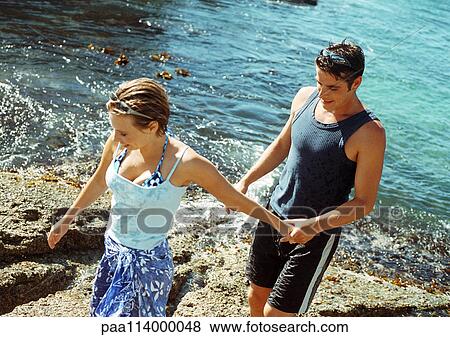 Stock Photo - Young couple at water's edge, high angle view. Fotosearch