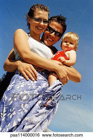Young couple holding baby, low angle view View Large Photo Image Stock Photograph - Young couple holding baby, low angle view. Fotosearch