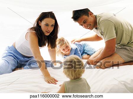 Stock Image - Couple and children in bedroom. Fotosearch