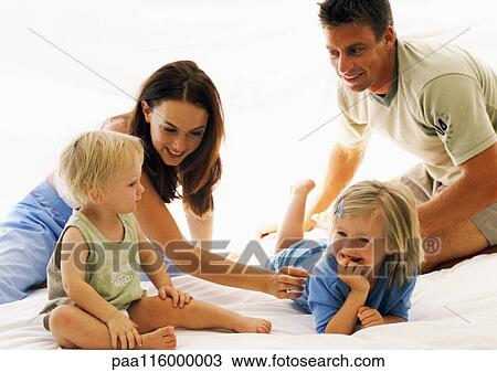 Stock Image - Couple and children on bed. Fotosearch