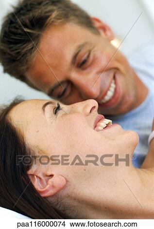 Couple resting in bed smiling, close-up View Large Photo Image Picture - Couple resting in bed smiling, close-up. Fotosearch
