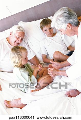 Grandparents and children sitting on bed View Large Photo Image Stock Image - Grandparents and children sitting on bed. Fotosearch