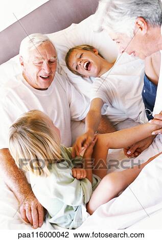 Grandparents and children sitting on bed, smiling View Large Photo Image Stock Image - Grandparents and children sitting on bed, smiling. Fotosearch