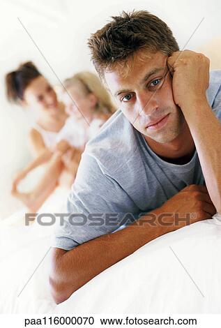 Man leaning head on hand, woman and child in background View Large Photo Image Stock Image - Man leaning head on hand, woman and child in background. Fotosearch