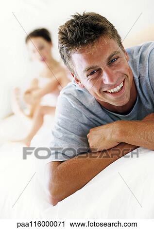 Man smiling, woman and child in background View Large Photo Image Stock Image - Man smiling, woman and child in background. Fotosearch
