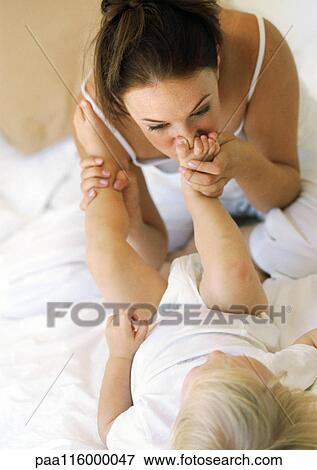 Mother kissing baby's foot View Large Photo Image Stock Photo - Mother kissing baby's foot. Fotosearch