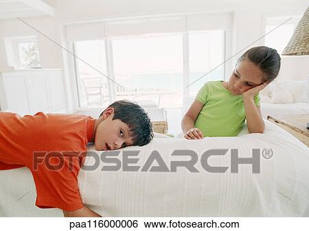 Stock Photograph - Two children resting on bed, one looking into camera. Fotosearch