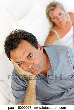 Woman sitting in bed behind man with hand on cheek View Large Photo Image Stock Photo - Woman sitting in bed behind man with hand on cheek. Fotosearch