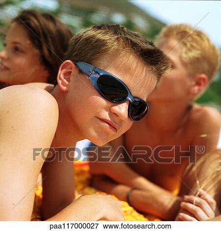Boy wearing sunglasses, friends in background View Large Photo Image Stock Photo - Boy wearing sunglasses, friends in background. Fotosearch