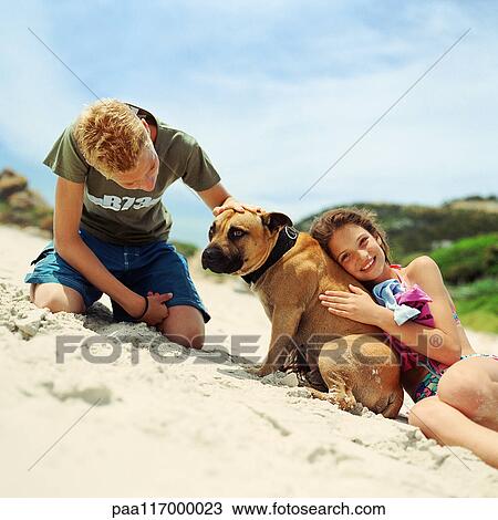 Stock Image - Children with dog on the beach. Fotosearch