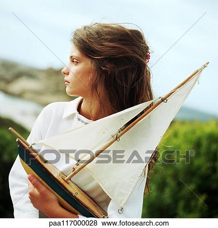 Stock Photo - Girl holding model boat, outside. Fotosearch