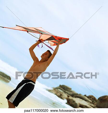 Teenage boy holding kite at the beach View Large Photo Image Stock Image - Teenage boy holding kite at the beach. Fotosearch