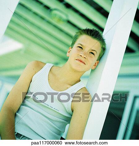 Stock Image - Teenage boy leaning back against post. Fotosearch