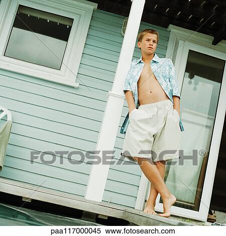 Teenage boy leaning on post in front of house, low angle view View Large Photo Image Stock Photography - Teenage boy leaning on post in front of house, low angle view. Fotosearch