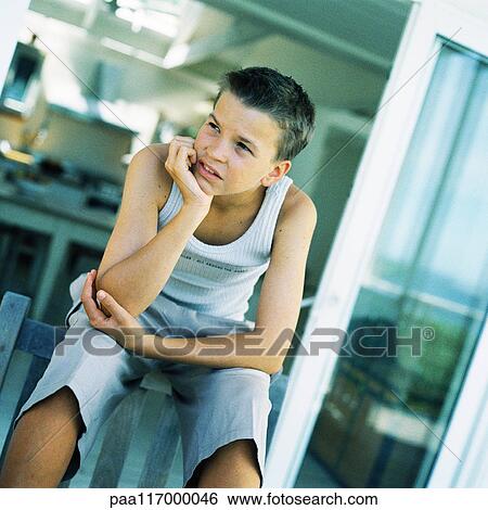 Teenage boy sitting with hand under chin View Large Photo Image Stock Photograph - Teenage boy sitting with hand under chin. Fotosearch