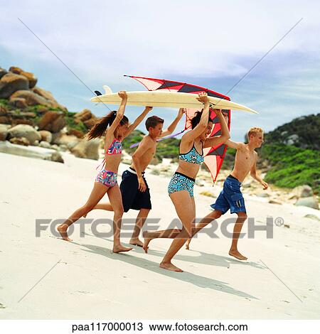 Teenagers and children in swimsuits holding surfboard and kite View Large Photo Image Stock Image - Teenagers and children in swimsuits holding surfboard and kite. Fotosearch