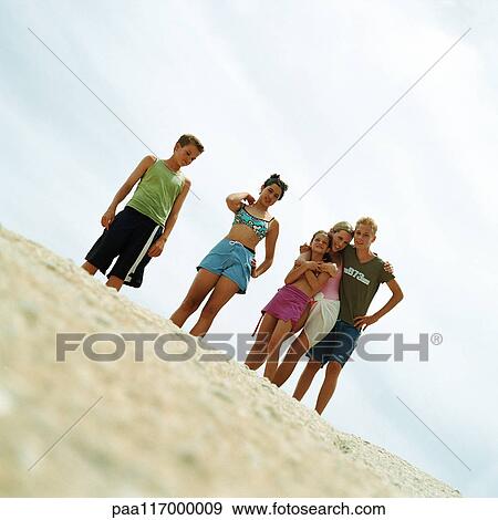 Teenagers in bathing suits standing on sand, low angle view View Large Photo Image Stock Photo - Teenagers in bathing suits standing on sand, low angle view. Fotosearch