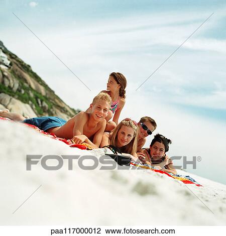 Teenagers lying on beach towels at the seashore View Large Photo Image Stock Image - Teenagers lying on beach towels at the seashore. Fotosearch