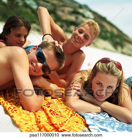 Stock Image - Teenagers lying on beach towels. Fotosearch