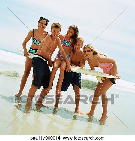 Teenagers on beach holding surfboard View Large Photo Image Picture - Teenagers on beach holding surfboard. Fotosearch