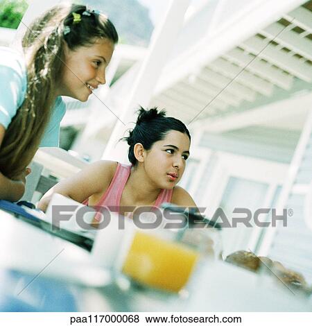 Stock Photo - Two girls sitting at table, outside. Fotosearch