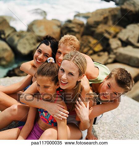 Stock Photography - Young people at the beach leaning on each other. Fotosearch