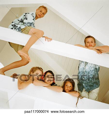 Young people in loft looking into camera, low angle view View Large Photo Image Picture - Young people in loft looking into camera, low angle view. Fotosearch