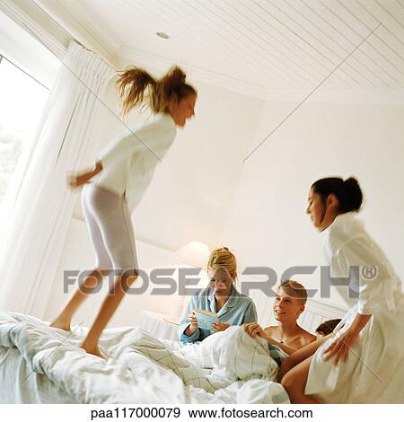 Young people on bed, playing around View Large Photo Image Stock Photo - Young people on bed, playing around. Fotosearch