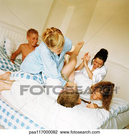 Young people playfighting on bed View Large Photo Image Stock Image - Young people playfighting on bed. Fotosearch